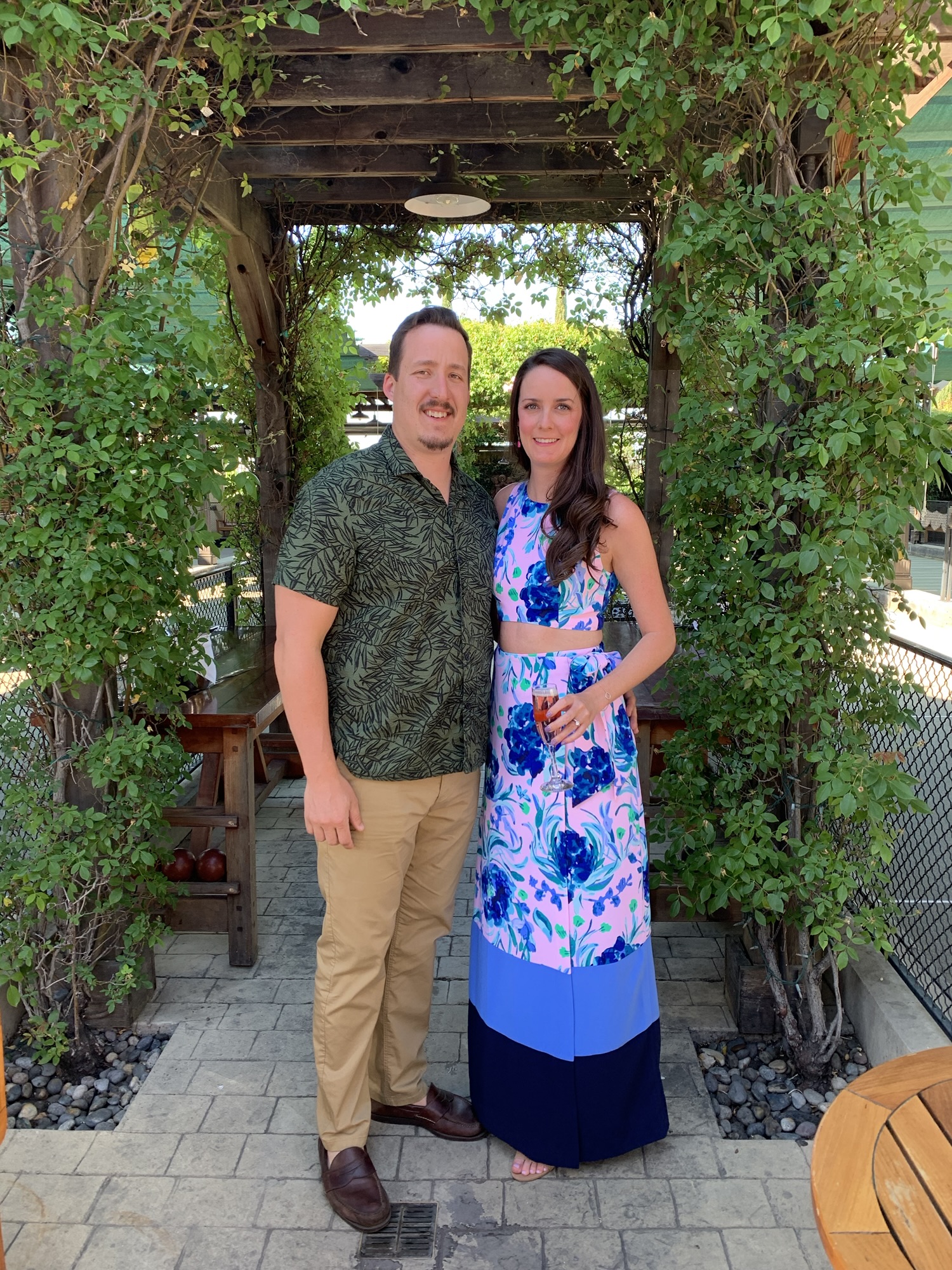 a couple posing in front of greenery