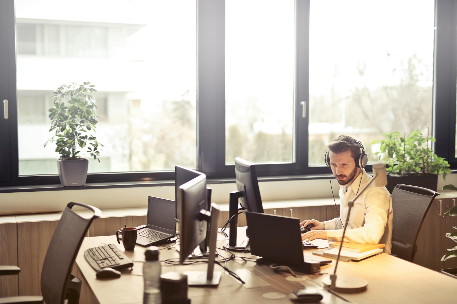 man on headphones in front of computer screens